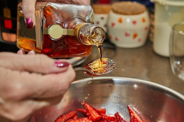 Chef pours liquor from bottle into sliced strawberries for dessert