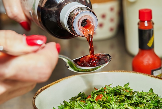 Photo chef pours pomegranate syrup with spoon to add to the salad