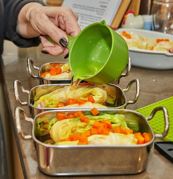 Chef pours sauce on cabbage rolls with salmon carrots in the kitchen French recipe