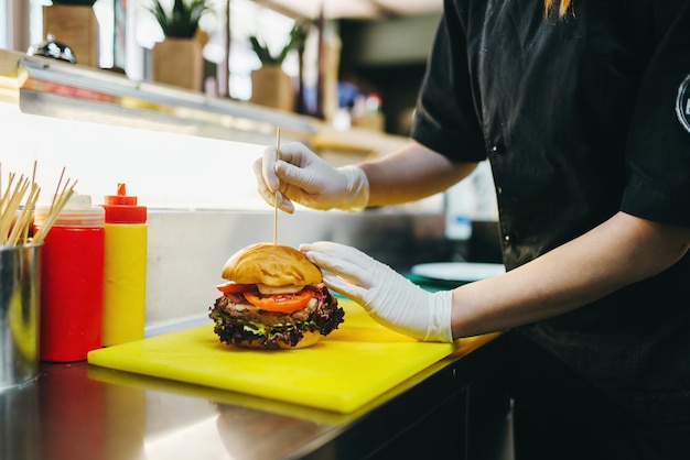 Photo chef prepares burger, fast food cooking. hamburger preparation process, fastfood