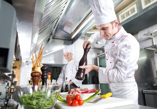 The chef prepares a dish in the kitchen of restoran.