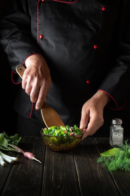 Lo chef prepara il cibo dalle verdure fresche in cucina insalata di lattuga preparata dalle mani dello chef