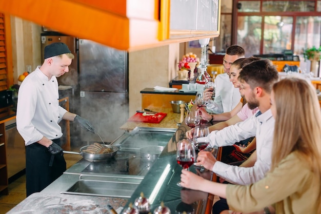 The chef prepares food in front of the visitors in the restaurant.