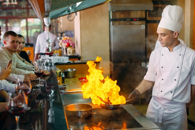 The chef prepares food in front of the visitors in the restaurant