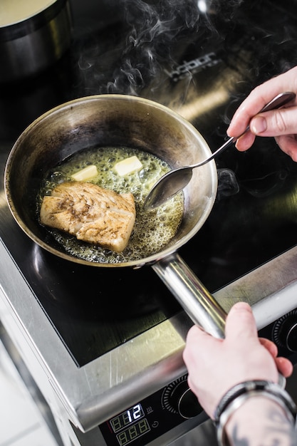 Chef prepares halibut under celery in the restaurant kitchen