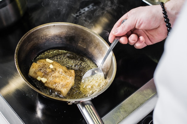 Chef prepares halibut under celery in the restaurant kitchen