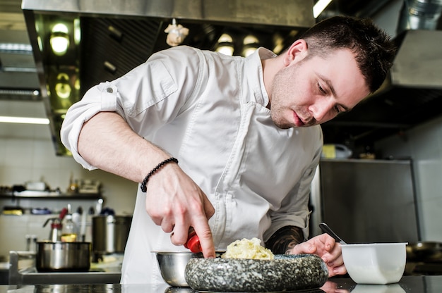 Chef prepares halibut under celery in the restaurant kitchen