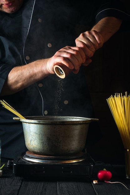 シェフが野菜を背景にイタリアンパスタを作る