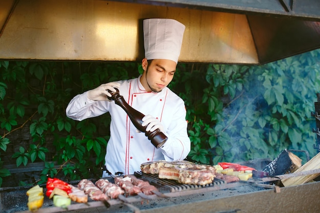 The Chef prepares meat on the barbecue.