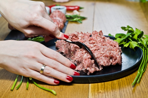 The chef prepares meatballs from raw minced meat.