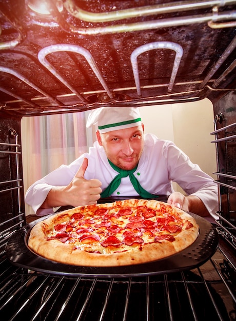 Chef prepares pizza in the oven, view from the inside of the oven. Cooking in the oven.