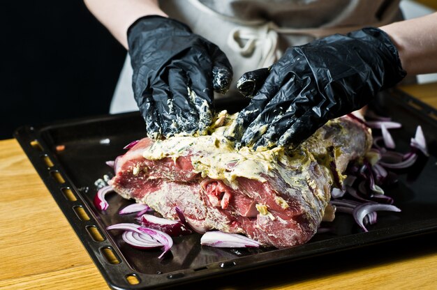 Lo chef prepara una gamba di agnello cruda.