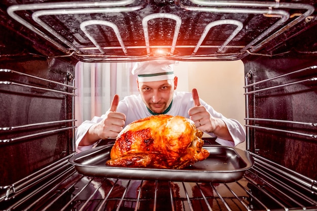 Chef prepares roast chicken (focus on chicken) in the oven, view from the inside of the oven. Cooking in the oven.Thanksgiving Day.