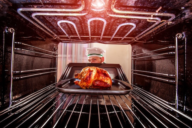 Chef prepares roast chicken in the oven, view from the inside of the oven. Cooking in the oven.