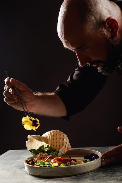 The chef prepares a salad of seafood and vegetables