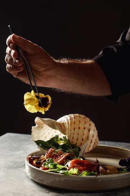 The chef prepares a salad of seafood and vegetables