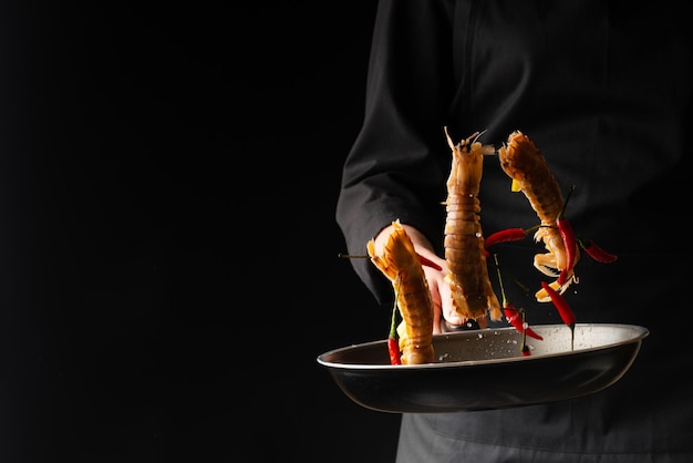 Chef prepares sea food mantis shrimp with lemon and hot pepper East Asian cuisine dilikates on a black background horizontal photo banner