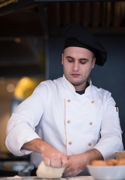 chef  preparing dough for pizza on table sprinkled with flour