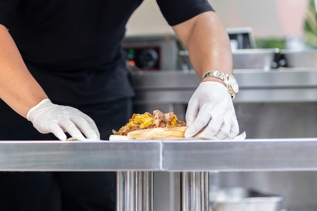 Chef preparing sandwich on food truck live cooking.