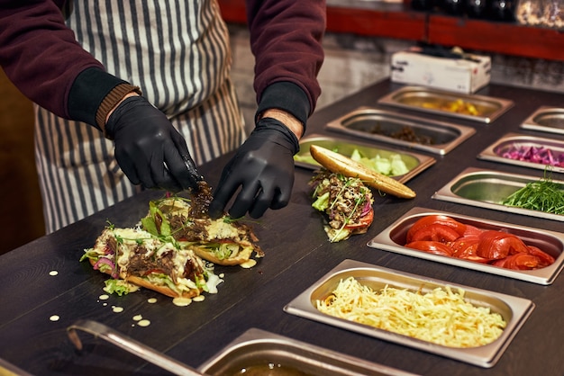 Uno chef che prepara un panino con insalata fresca. corte alimentare della fiera di strada. cucina all'aperto