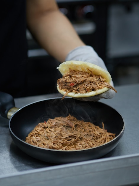 Foto chef che prepara arepa venezuelana farcita con carne sminuzzata