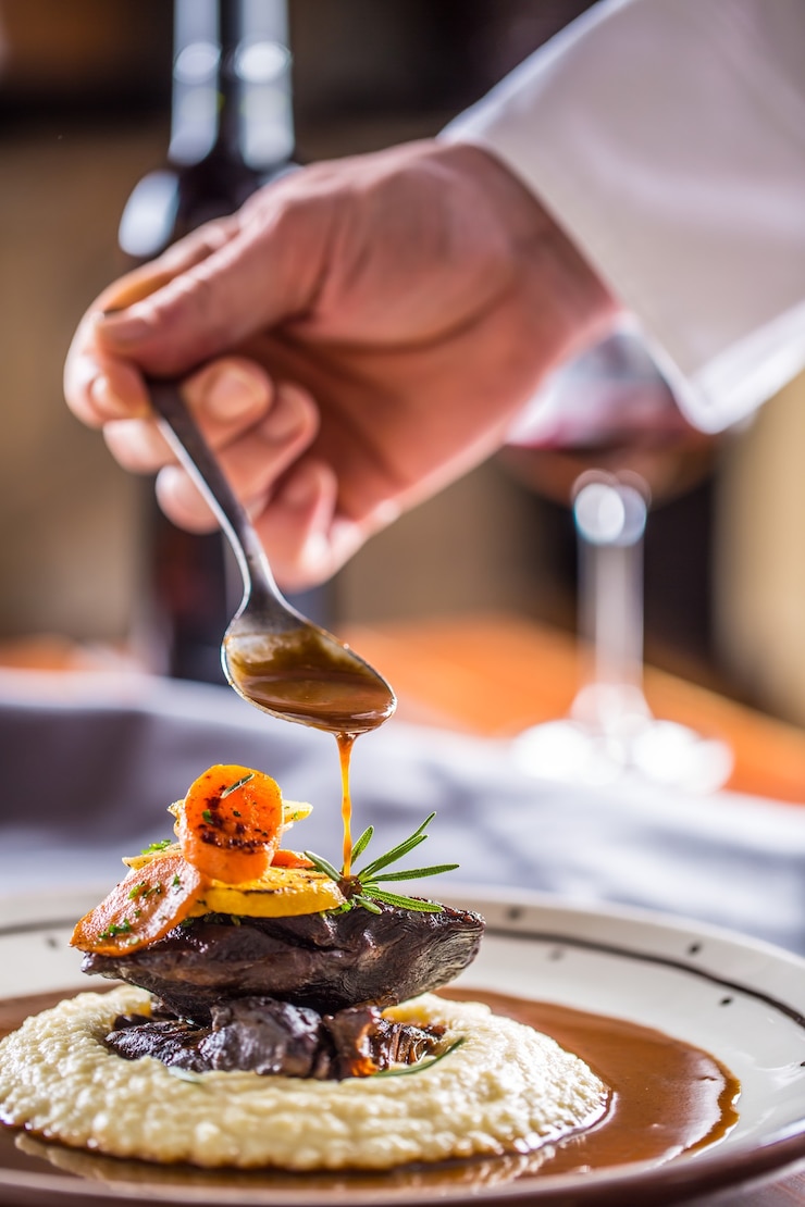 Photo chef in pub or restaurant decorates portion of the meal in pup or restaurant.