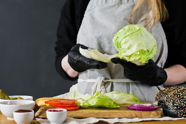 The chef pulls the lettuce. The concept of cooking a black Burger. Homemade hamburger recipe. 