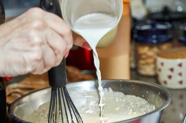 The chef puts milk in dough bowl to make baked goods with asparagus and peas. Step by step recipe.