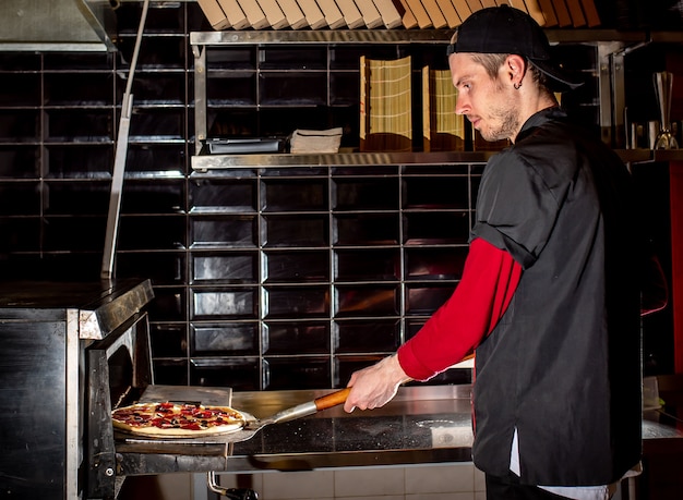 Chef putting pizza in oven for cooking