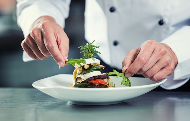 Chef in restaurant garnishing vegetable dish