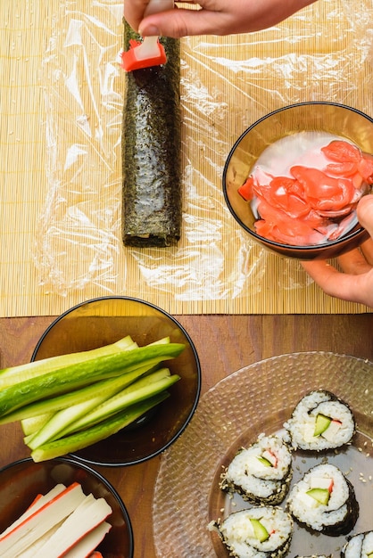 The chef of the restaurant is anointing the brush of the sauce on the role of sushi