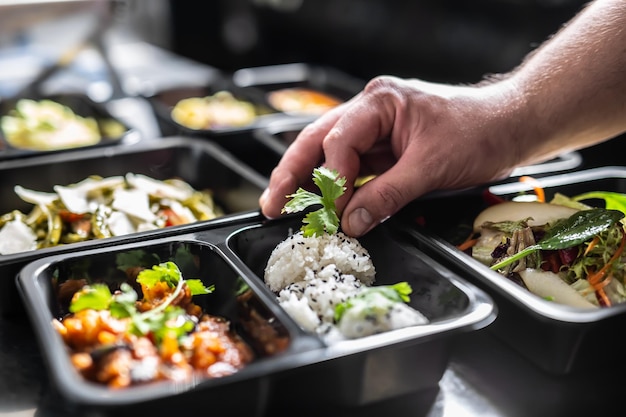 The chef in restaurant kitchen finishes the food ready for delivery in takeaway packages.