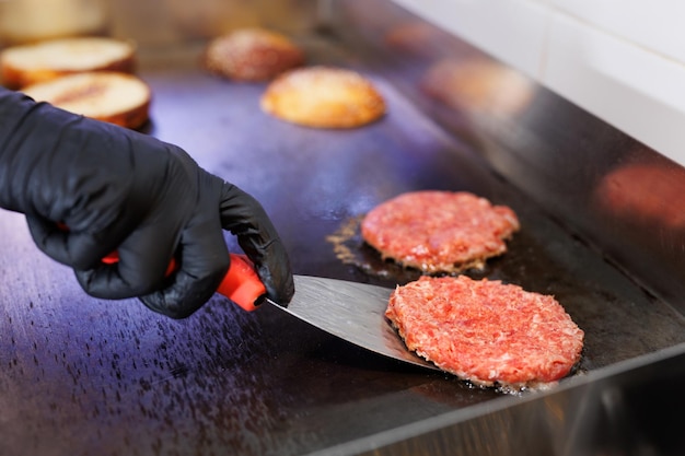 Foto lo chef arrostisce le cotolette di carne per gli hamburger nella cucina del ristorante