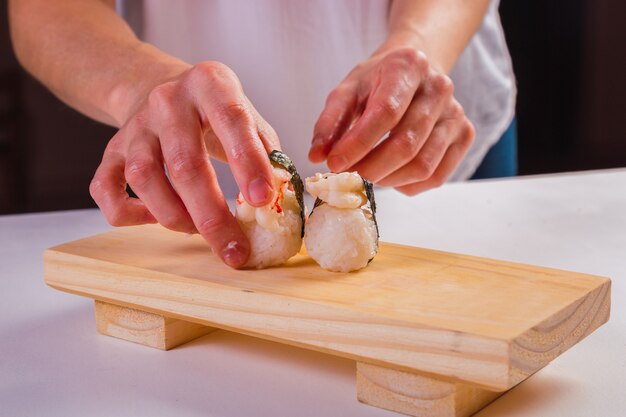 Foto chef's hand regelen sushi roll op houten bord.