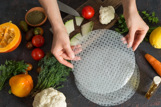 Chef's handen koken rolt stappen in rijstpapier en verschillende plantaardige vullingen.