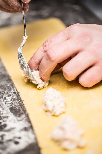 Chef's hands prepares Italian food stuffed pasta ravioli.