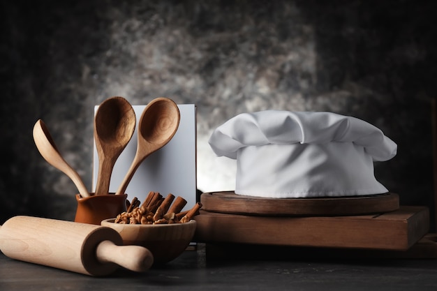 Chef's hat with  kitchenware on dark