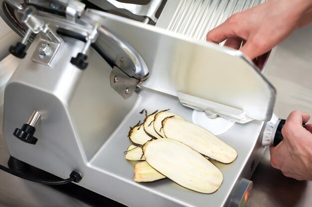 Chef's work on a slicer slicing vegetables