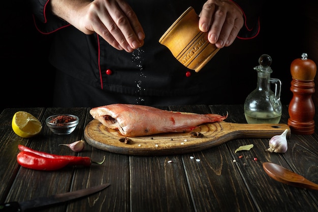 The chef salts fresh Sebastes in the kitchen before baking