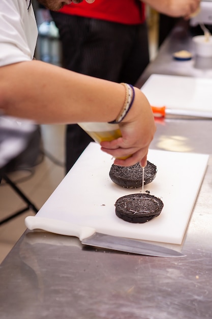 Foto chef condimento di un panino di hamburger nero nel ristorante della cucina