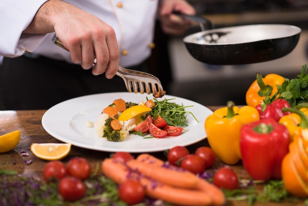 chef serving vegetable salad on plate in restaurant kitchen