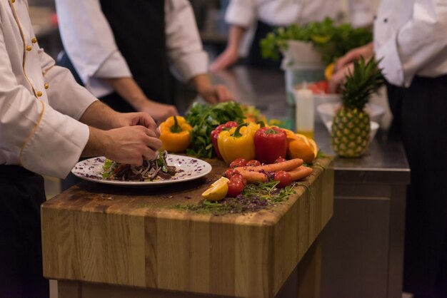 chef serving vegetable salad on plate in restaurant kitchen