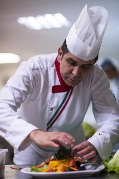 chef serving vegetable salad on plate in restaurant kitchen