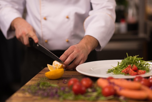 Photo chef serving vegetable salad on plate in restaurant kitchen