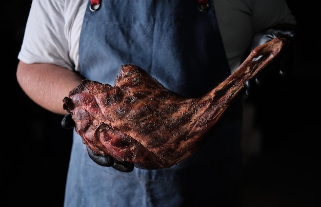 Foto chef che mostra la spalla di agnello affumicato