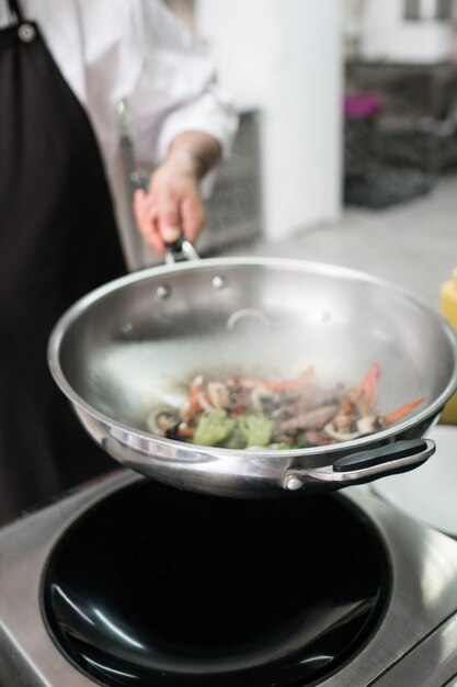 Chef showing off his professional skills. Cooking master at work in restaurant kitchen.