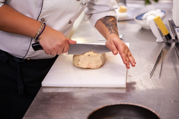 Lo chef affetta il foie gras intero nella cucina del suo ristorante