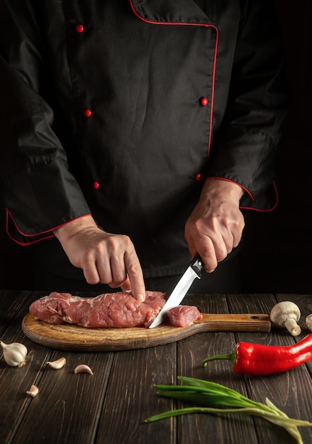 Chef snijdt rauw rundvlees op een snijplank voor het bakken Vrije ruimte voor hotelmenu of recept