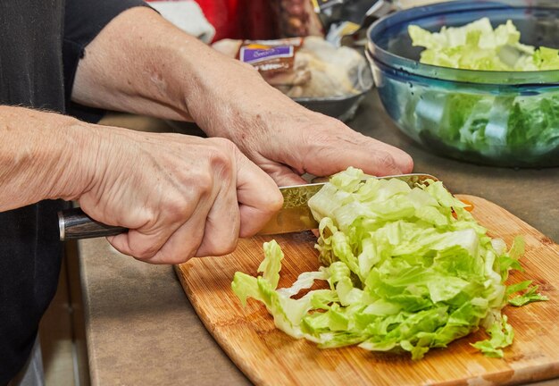 Chef snijdt sla op een houten bord in de thuiskeuken