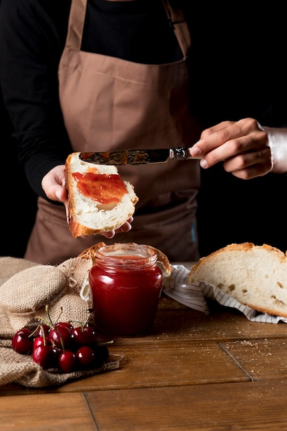 Foto chef diffondendo la marmellata di amarene sul pane